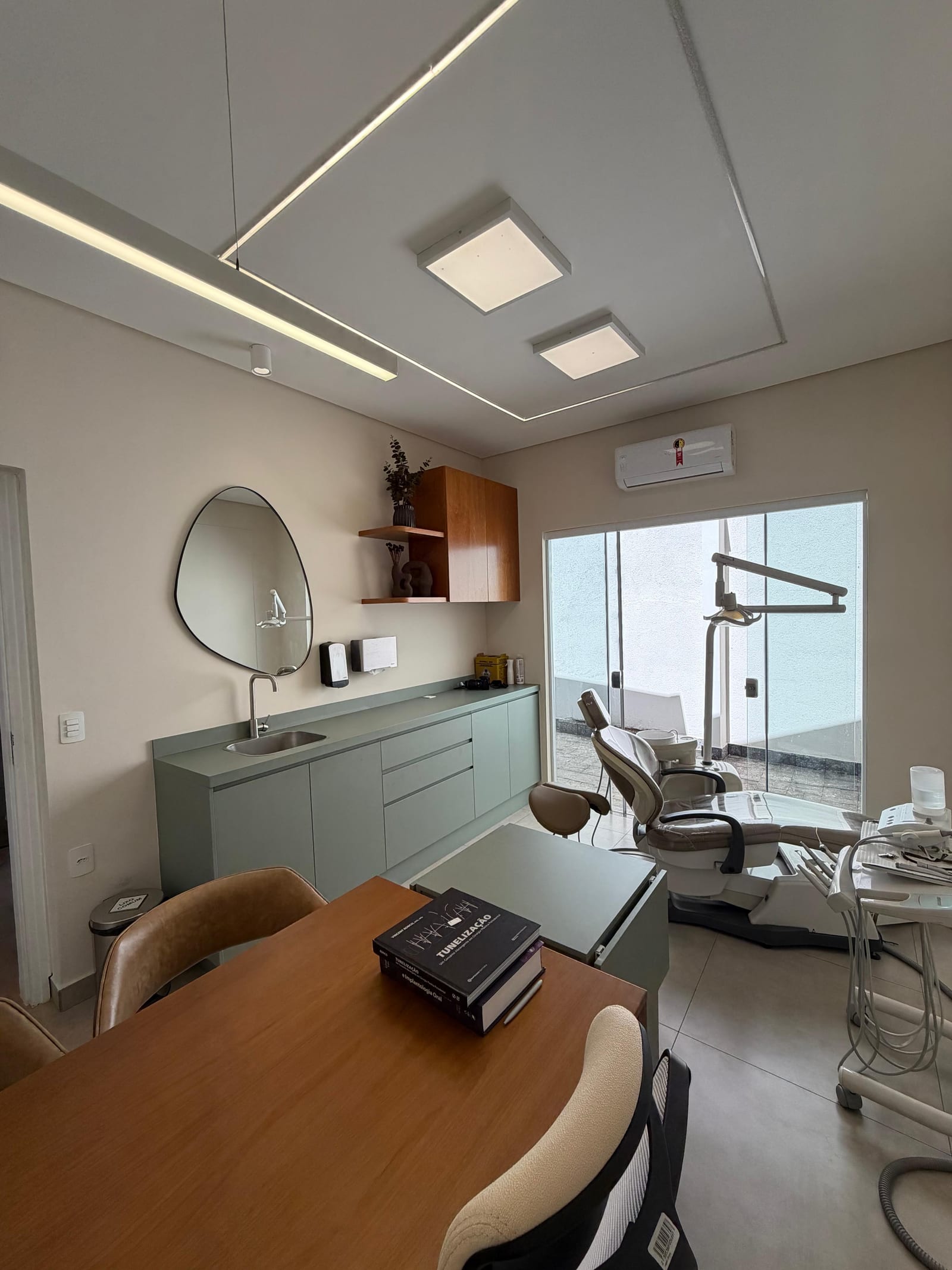 Consultório da Clínica Paraluppi: cadeira odontológica, armários verdes e luz natural pela janela.