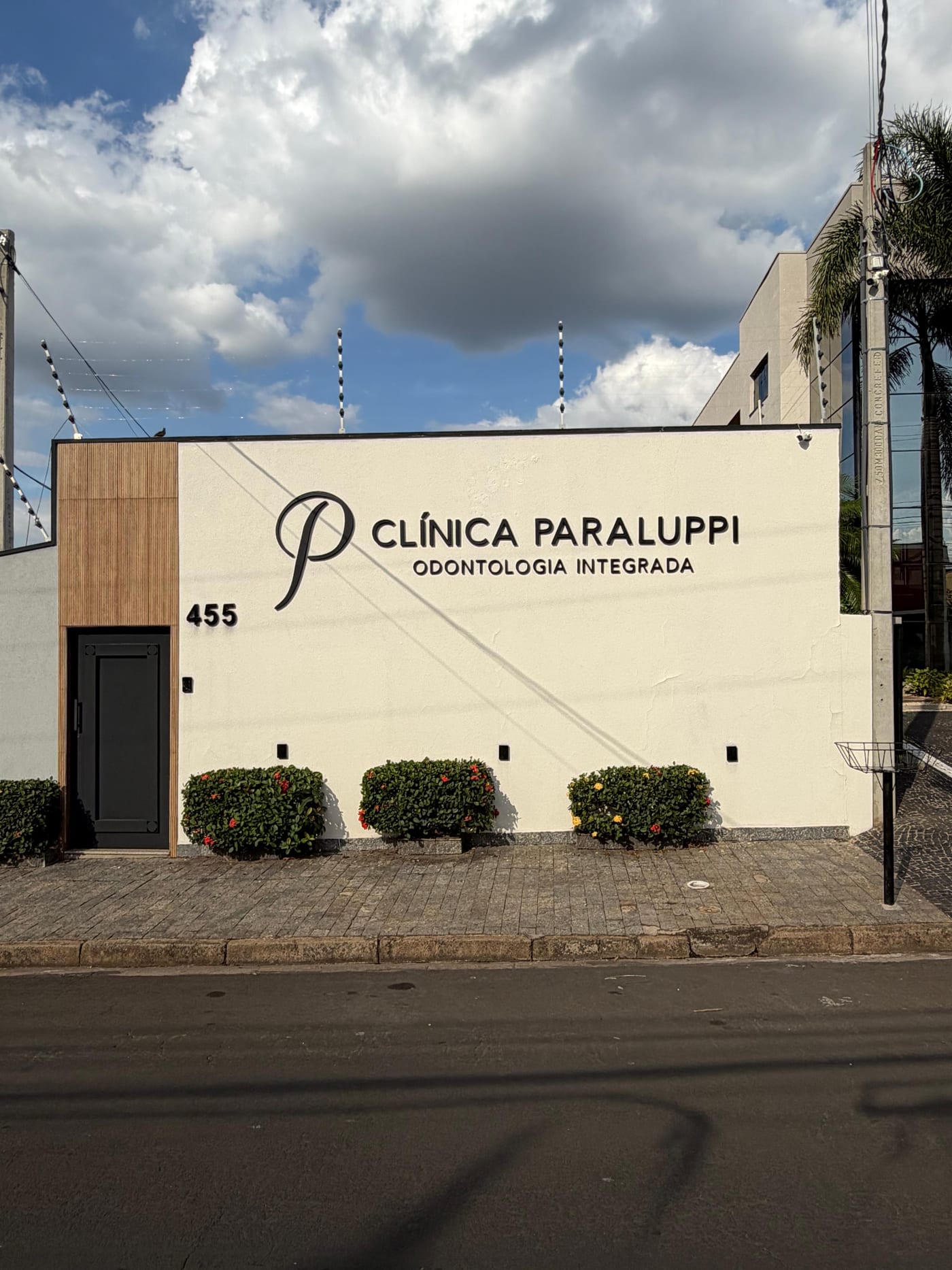 Fachada da Clínica Paraluppi, com painel de madeira, porta preta e o número 455.