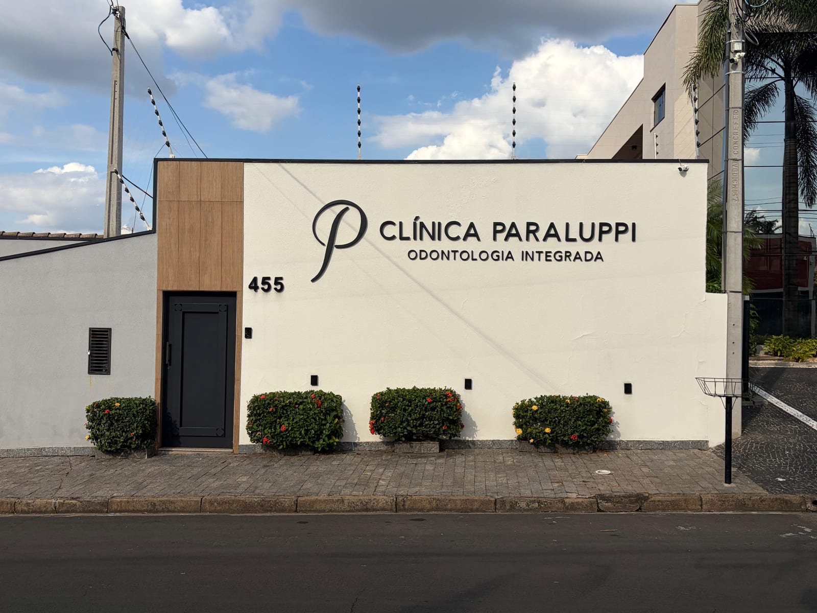 Fachada da Clínica Paraluppi vista da calçada, com jardim baixo em frente.