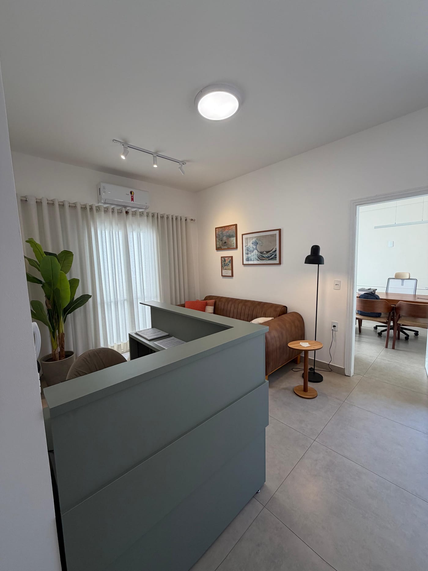 Sala de espera da clínica, com sofá de couro e quadros na parede.